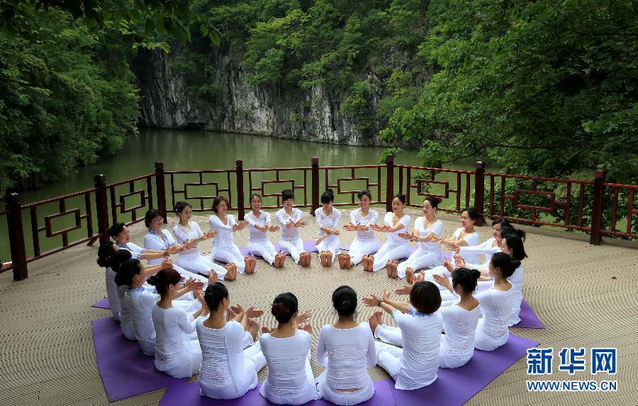 Practicing yoga among green hills and clear water