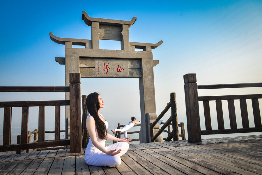 Striking yoga poses on top of cliff