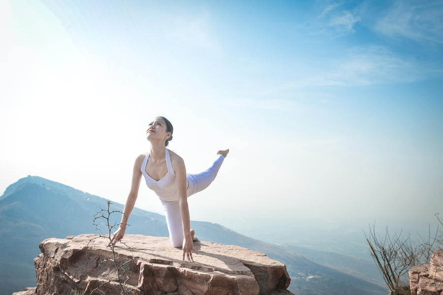 Striking yoga poses on top of cliff