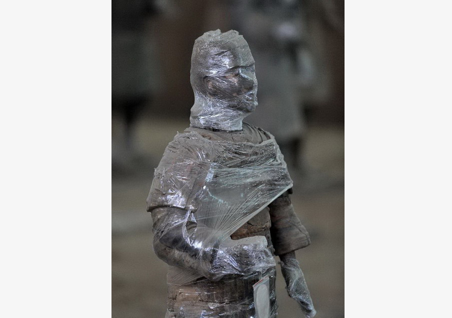 Terracotta warriors wrapped in cling film for protection of remnant painting