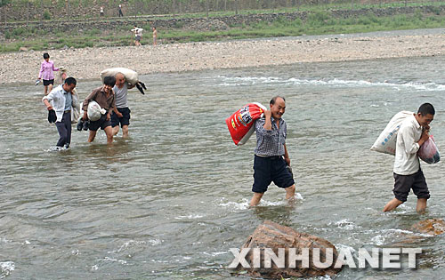 嵩縣木植街鄉(xiāng)的部分深山獨(dú)居戶涉水下山，準(zhǔn)備搬入新居（2002年6月26日攝）。 河南省嵩縣是國(guó)家扶貧工作重點(diǎn)縣。為徹底改變部分生活在深山區(qū)、被“行路難、用電難、吃水難、上學(xué)難、就醫(yī)難”困擾的村民的生活狀況，從2002年開始，嵩縣把“異地安置、搬遷扶貧”作為山區(qū)扶貧開發(fā)的切入點(diǎn)和深山群眾脫貧致富的途徑，有計(jì)劃、分期分批地把他們搬遷到小城鎮(zhèn)和交通便利的村莊。5年來，嵩縣通過多種形式，新建移民新村53個(gè)，遷出深山貧困群眾3238戶、13151人。 新華社記者 王頌攝 