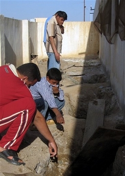 Iraqi schoolchildren inspect holes where buried bodies were found, in their school yard in Ramadi, 115 kilometers (70 miles) west of Baghdad, Iraq, Tuesday, April 17, 2007. 